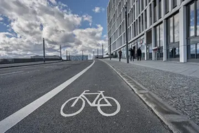 Radweg in einer städtischen Umgebung, markiert durch ein Fahrradpiktogramm.