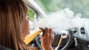 weibliche Person mit E-Zigarette am Steuer 