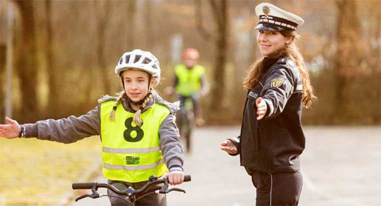 mädchen auf fahrrad neben einer polizistin