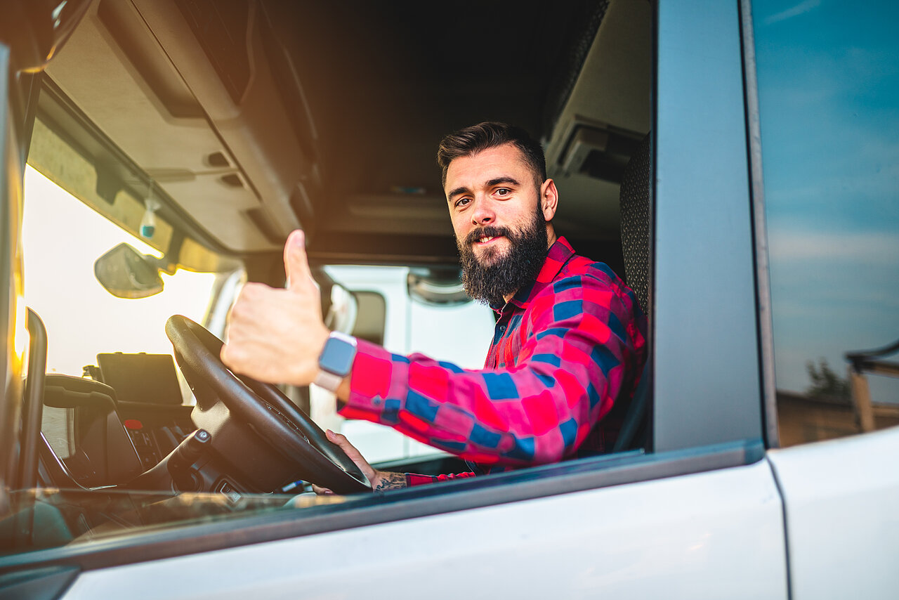 lkw-fahrer im lkw zeigt den daumen hoch