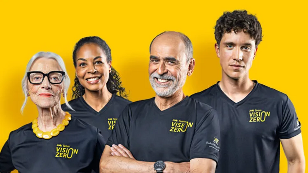 Vier Personen im "Team Vision Zero" T-Shirt vor gelbem Hintergrund.