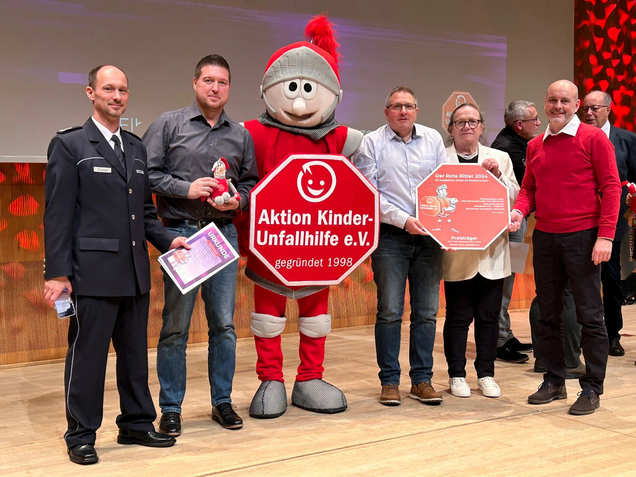 Gruppenfoto mit den Preisträgern und dem Roten Ritter mehrere Personen stehen zusammen mit dem Maskottchen "Roter Ritter" auf der Bühne