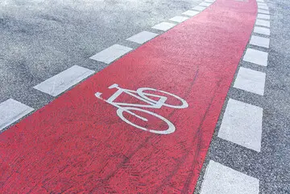 Roter Radweg mit einem Fahrradpiktogramm und weißer Begrenzung.